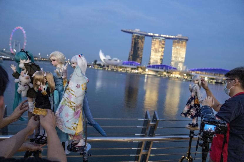 Fotografer menempatkan boneka anime Jepang dengan latar belakang Marina Bay Sands di Singapura, Sabtu, 15 Juli 2023. Menurut Henley Passport Index, paspor Singapura menduduki peringkat teratas sebagai yang terkuat di dunia.