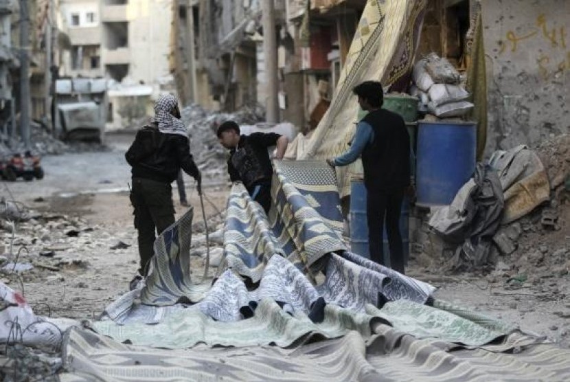 Free Syrian Army fighters pull carpets along a rubble-filled street as they prepare to use them as curtains to provide cover from snipers loyal to Syria's President Bashar al-Assad in Deir al-Zor, eastern Syria February 11, 2014.