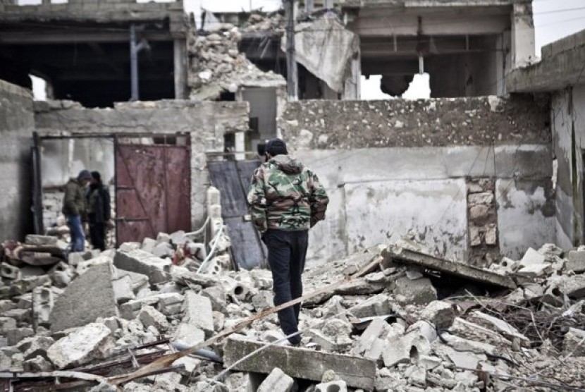 Free Syrian Army fighters walk amid the ruins of a village situated a short distance from an area where fighting between rebels and government forces continues, Saturday, Dec. 22, 2012.  
