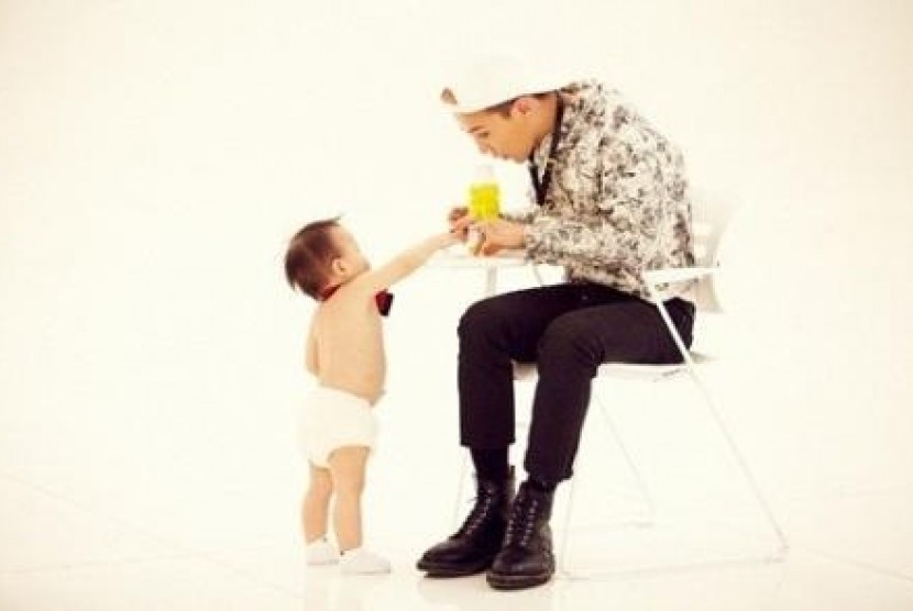 G-Dragon saat tampil dalam iklan bersama bayi lucu