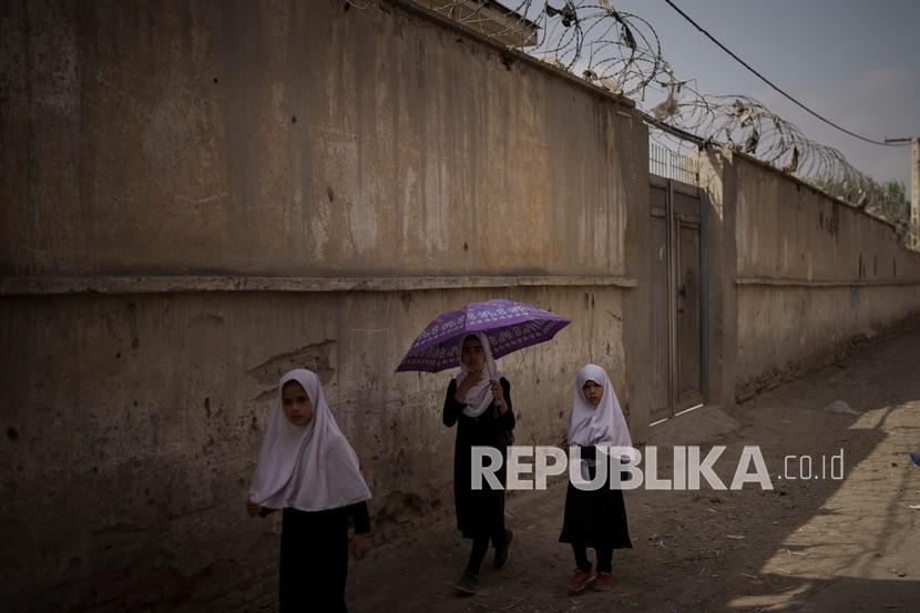 Anak-anak perempuan berjalan ke sekolah mereka sebelum kelas di Kabul, Afghanistan, Ahad (12/9).