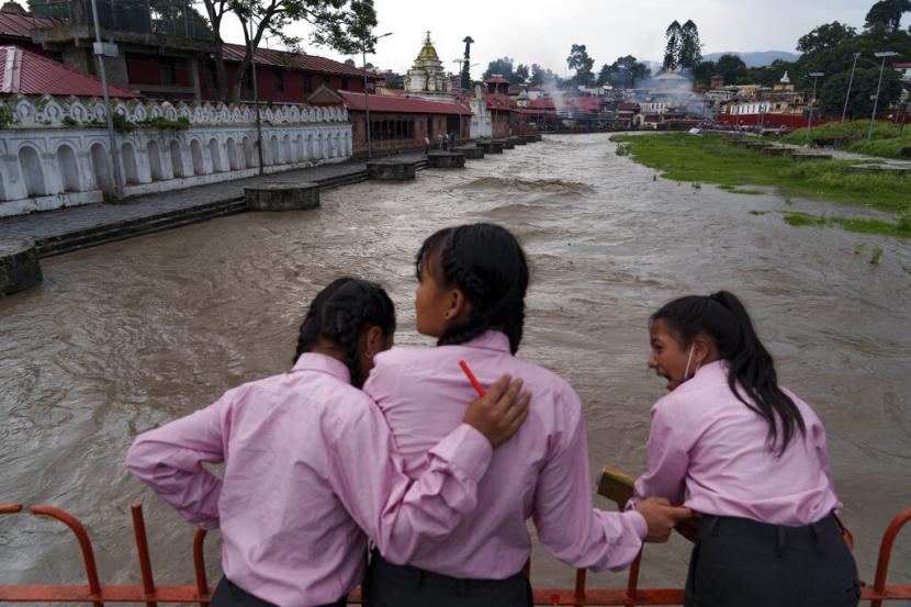 Gadis-gadis melihat Sungai Bagmati, yang meluap karena hujan monsun, di Kathmandu, Nepal, Rabu, 27 Juli 2022. Seorang ibu dua anak dari Nepal Parwati Sunar mendapati dirinya bersekolah di sekolah yang sama dengan putranya setelah kembali ke sistem pendidikan yang ditinggalkannya pada usia 15 tahun.