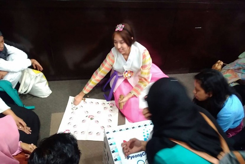Gadis Korea menunjukkan cara bermain yut nori, salah satu permainan tradisional negaranya 