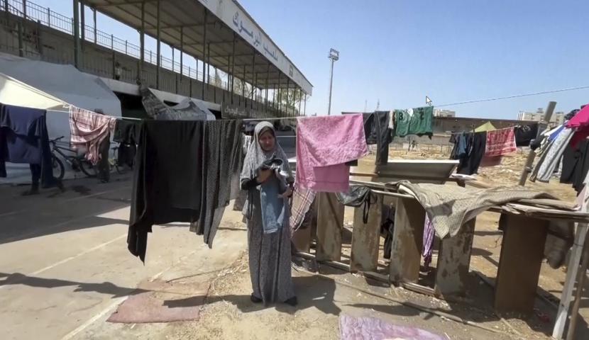 Gambar menunjukkan seorang wanita sedang menjemur pakaian, Jumat, 5 Juli 2024 di Stadion Olahraga Yarmouk, Jalur Gaza, Palestina, yang dulunya merupakan stadion sepak bola aktif di Gaza. Kini menjadi tempat penampungan bagi ribuan warga Palestina yang mengungsi dan hanya memiliki sedikit makanan atau air.