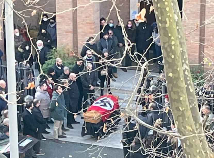  Gambar yang diperoleh dari portal media online Itali menggambarkan bagaimana orang-orang berkumpul di depan peti mati yang ditutupi bendera Nazi di depan Gereja St. Lucia di Roma, Selasa (11/1/2022). 