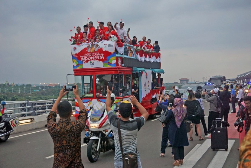 Ganda campuran bulutangkis peraih medali emas Olimpiade Brasil, Tontowi Ahmad (keempat kanan) dan Liliyana Natsir (ketiga kiri) diarak menggunakan bus bandros setibanya di Terminal 3 baru Bandara Soekarno-Hatta, Tangerang, Banten, Selasa (23/8).