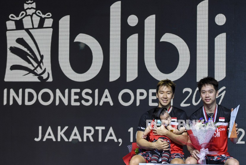 Ganda putra Indonesia Marcus Fernaldi Gideon (kiri) dan Kevin Sanjaya Sukamuljo menunjukan piala di atas podium usai bertanding mengalahkan ganda putra Indonesia Mohammad Ahsan dan Hendra Setiawan pada final Blibli Indonesia Open 2019 di Istora Gelora Bung Karno, Jakarta, Ahad (21/7/2019).