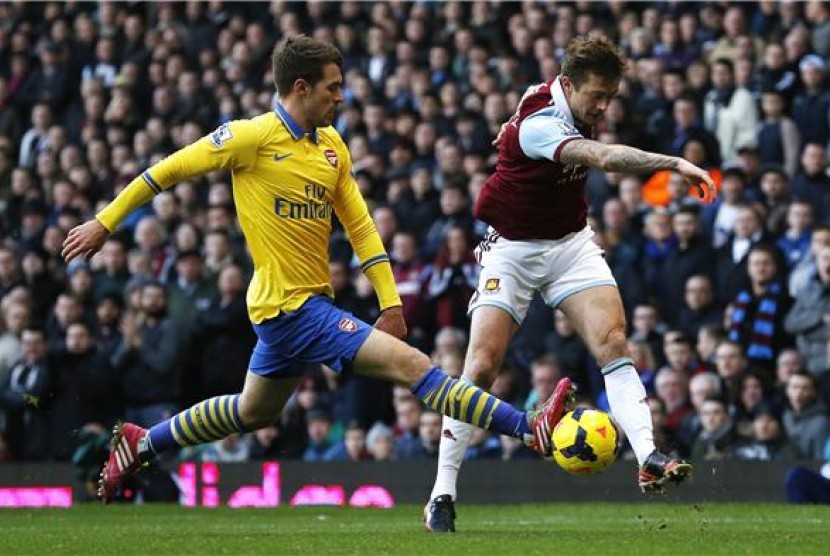 Gelandang Arsenal, Aaron Ramsey, menghadang pergerakan pemain West Ham United, George McCartney, dalam laga Liga Primer Inggris di Upton Park, London, Kamis (26/12). 