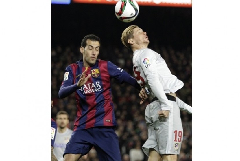 Gelandang Barcelona Sergio Busquets (kiri) saat berduel dengan penyerang Atletico Madrid Fernando Torres dalam laga Copa Del Rey, Kamis (22/1) WIB.
