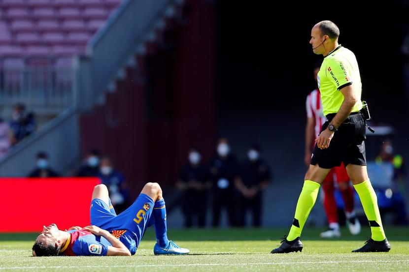 Gelandang Barcelona Sergio Busquets (kiri) terkapar setelah bertubrukan dengan pemain lawan ketika menghadapi Atletico Madrid di Camp Nou, Sabtu (8/5).