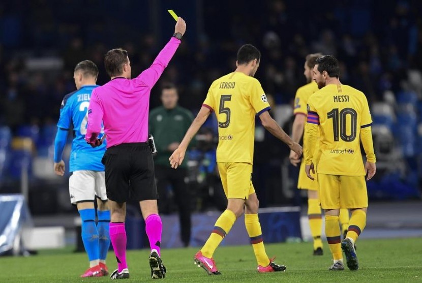 Gelandang Barcelona Sergio Busquets (tengah) menerima kartu kuning saat melawan Napoli. Barcelona ditahan imbang Napoli 1-1 pada leg pertama babak 16 besar Liga Champions.