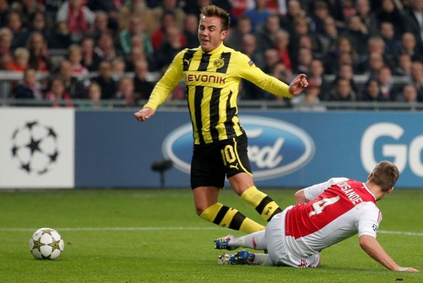 Gelandang Dortmund Mario Gotze ditekel Niklas Moisander dalam lanjutan Liga Champions Kamis (22/11) dini hari. Dortmund kalahkan Ajax 4-1 di Amsterdam Arena