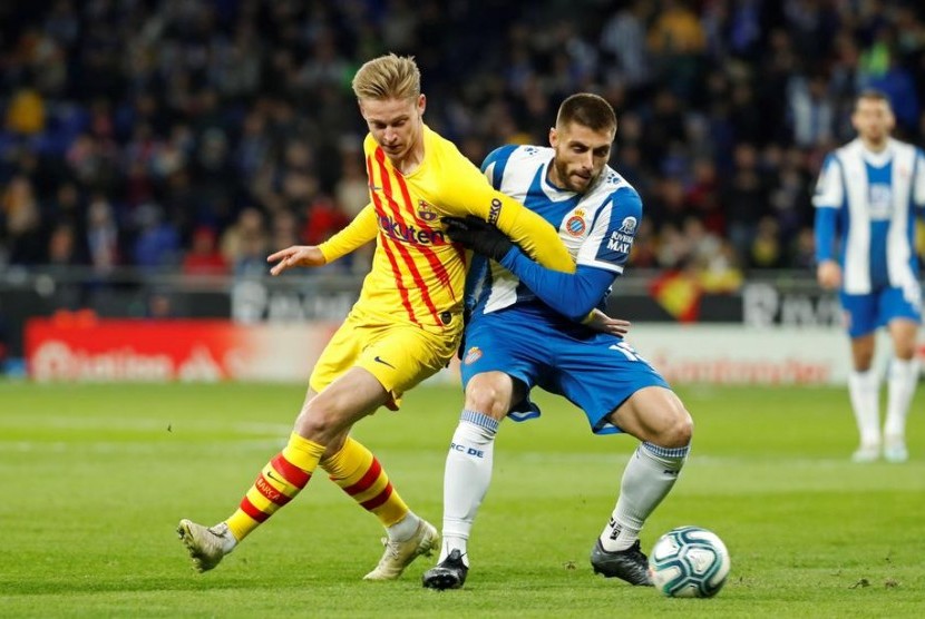 Gelandang Espanyol David Lopez (kanan) berebut bola dengan gelandang Barcelona Frankie De Jong. Lopez mencetak gol Espanyol ke gawang Barcelona di Stadion RCDE, Barcelona, Ahad (5/1) dini hari WIB.