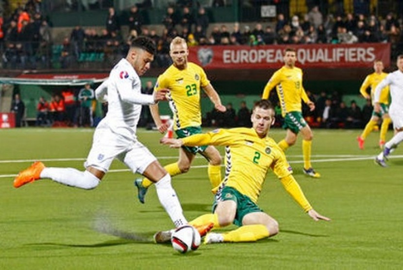 Gelandang Inggris Alex Oxlade Chamberlain yang membawa bola diadang pemain Lithuania Linas Klimavicius.