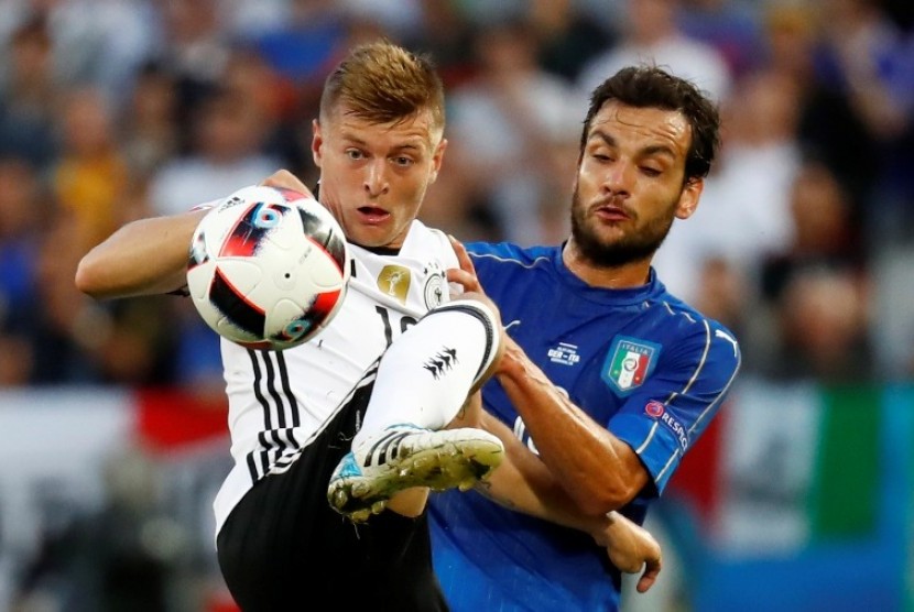 Gelandang Jerman Toni Kroos (kiri) berebut bola dengan gelandang Italia Marco Parolo.