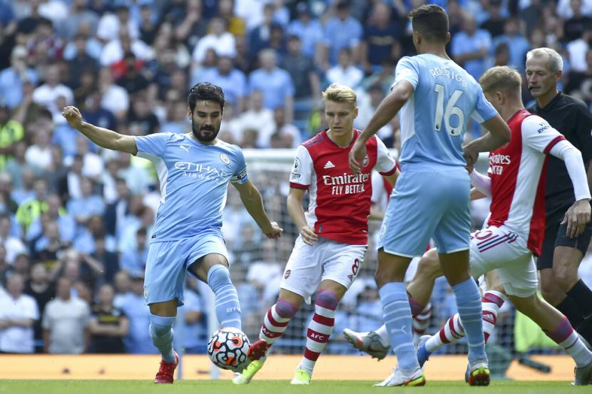 Gelandang Manchester City Ilkay Guendogan (kiri) berebut bola dengan pemain Arsenal. Guendogan mencetak gol pertama City melawan Arsenal dalam lanjutan Liga Primer Inggris, Sabtu (28/8).