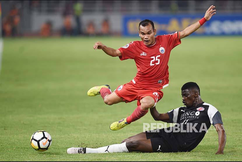 Gelandang Persija Jakarta Riko Simanjuntak (atas) mencoba melewati hadangan pesepak bola Home United Sirina Camara (bawah)