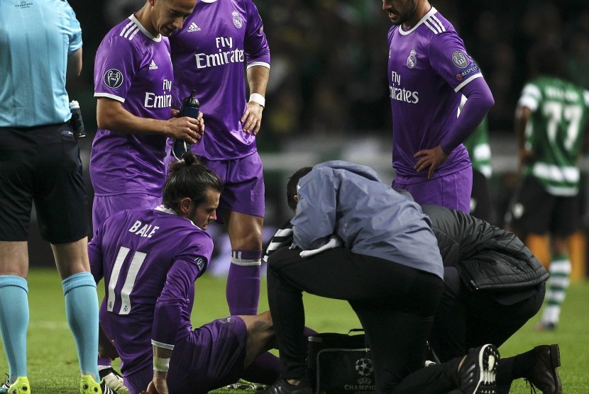 Gelandang Real Madrid, Gareth Bale (duduk) mendapatkan perawatan seusai diganjal bek Sporting Lisbon pada laga Liga Champions, di stadion Jose Alvalede, Lisbon, 23 November 2016.. 