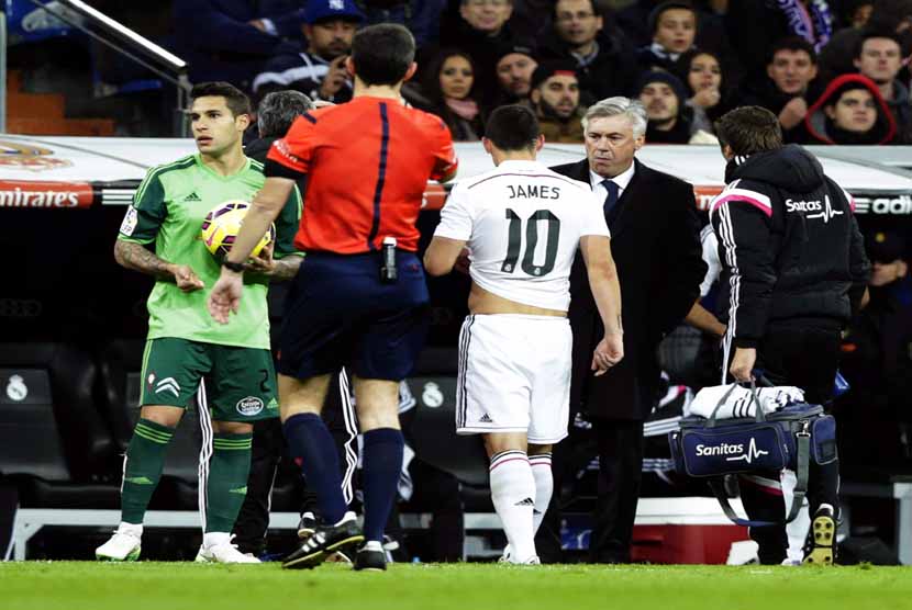 Gelandang Real Madrid, James Rodriguez (tengah), ditarik keluar lapangan akibat mengalami cedera saat menghadapi Celta Vigo dalam laga La Liga Spanyol di Santiago Bernabeu, Madrid, Sabtu (6/12). 