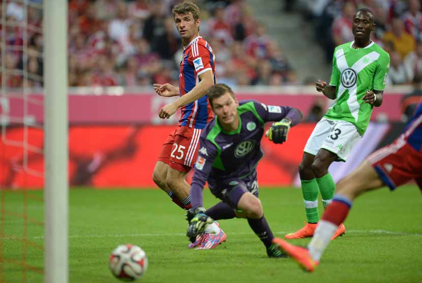 Gelandang serang Bayern Muenchen, Thomas Mueller (kiri), menjebol gawang VfL Wolfsburg dalam laga pembuka kompetisi Bundesliga Jerman di Muenchen, Jerman, Jumat (22/8). 