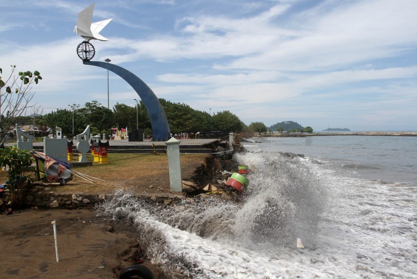 Gelombang tinggi menghantam tembok pembatas tugu di pantai (ilustrasi) 