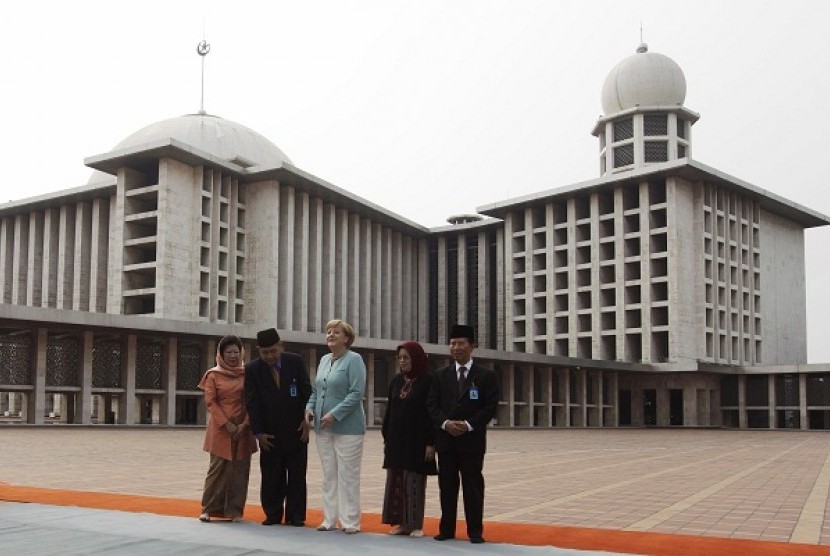German Chancellor Angela Merkel (center) stands as she pose for a photograph with Indonesian Trade Minister Mari Elka Pangestu (left) and mosque officials during her visit to Istiqlal Mosque in Jakarta July 10, 2012.   Reuters/Beawiharta
