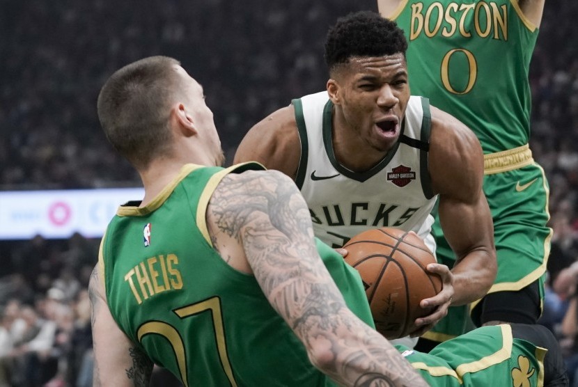 Bintang Milwaukee Bucks Giannis Antetokounmpo (tengah) mempertahankan bola dari pemain Boston Celtics dalam lanjutan kompetisi NBA.