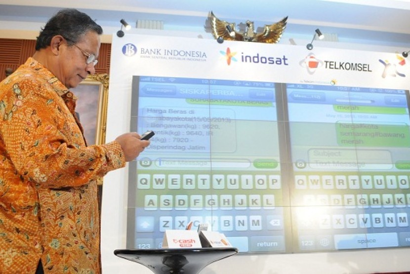 Governor of Bank Indonesia, Darmin Nasution, demonstrates how to use e-money system. Three biggest telecommunication operators in Indonesia collaborate to provide e-money service using short message service (SMS).  