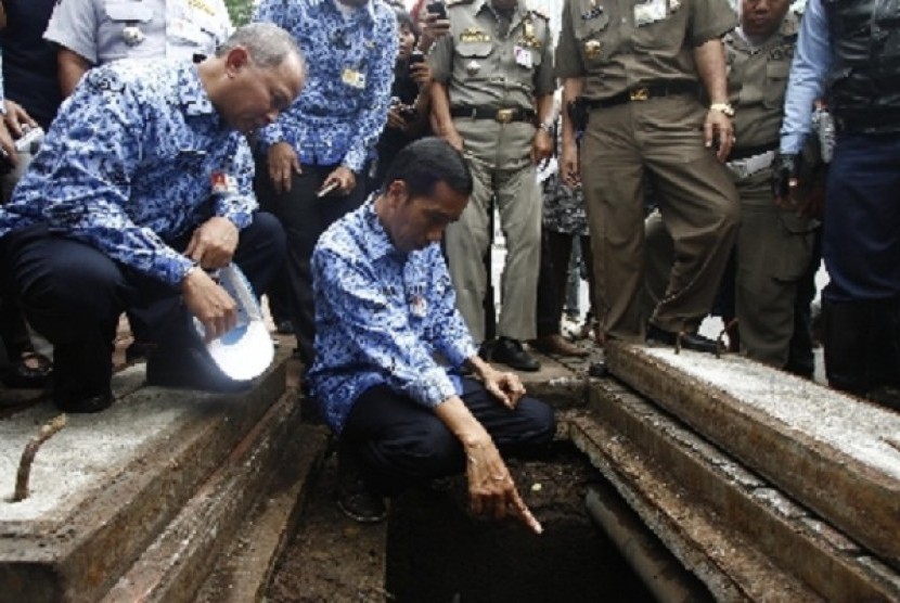 Governor of Jakarta Joko Widodo (center-front) checks teh semage system in MH Thamrin Street in Central Jakarta on Wednesday after the earlier rains inundate the street.   