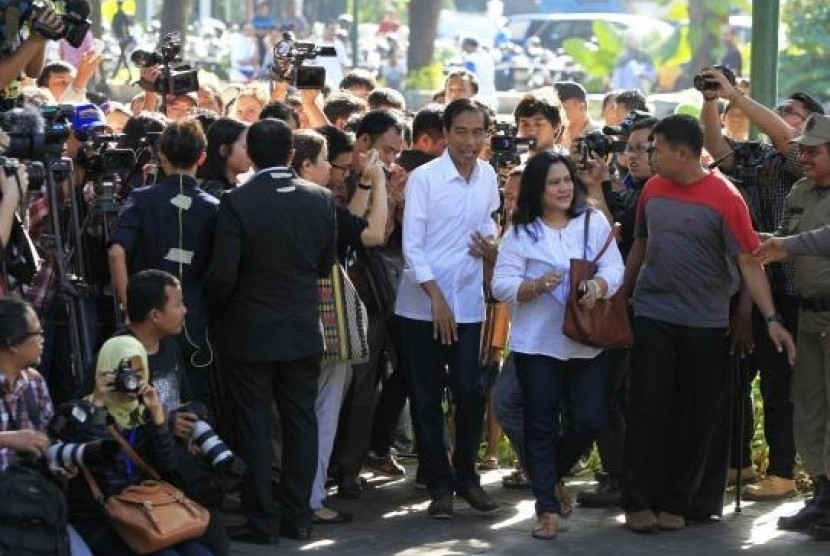 Governor of Jakarta who also a presidential candidate from the Indonesian Democratic Party for Struggle (PDIP) party, Joko Widodo, and his wife Iriana (both in white) arrive to vote in the parliamentary elections, at a polling station in Jakarta April 9, 2