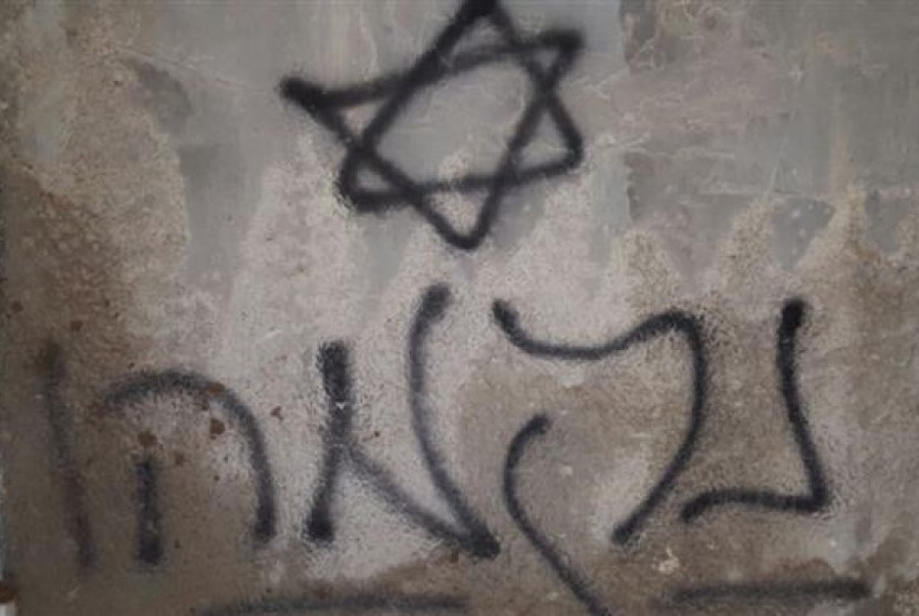 Grafiti bintang daud yang tertera di dinding rumah warga Palestina yang terbakar di Duma, dekat Nablus, Jumat (31/7).