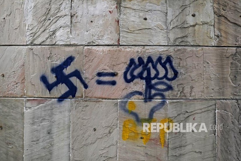 Grafiti menyandingkan lambang swastika nazi dengan logo partai penguasa terpampang di tembok di kampus Jamia Millia Islamia University, New Delhi, India. Seniman Italia memodifikasi mural lambang swastika sebagai simbol melawan rasisme. Ilustrasi.