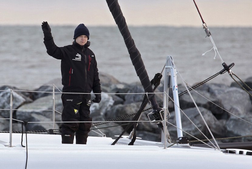 Greta Thunberg melambaikan tangannya di atas kapal katamaran La Vagabonde saat berlayar keluar dari Salt Ponds di Hampton, Virginia, Amerika, Rabu (13/11).