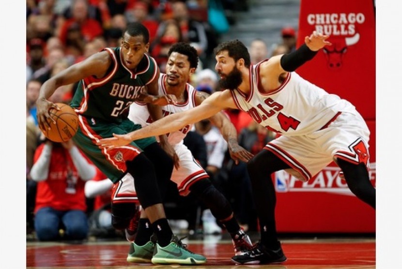 Guard Milwaukee Bucks Khris Middleton (kiri) berusaha menjaga bola dari guard Chicago Bulls Derrick Rose (tengah) dalam lanjutan play-off NBA.