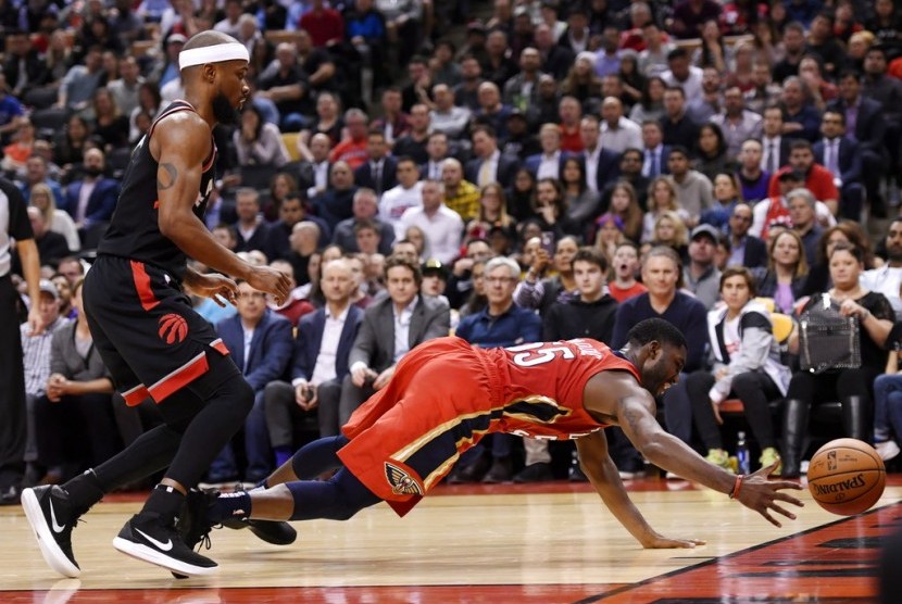 Guard New Orleans Pelicans Jrue Holiday (kanan) berusaha menyelamatkan bola saat bertemu Toronto Raptors di kompetisi NBA.