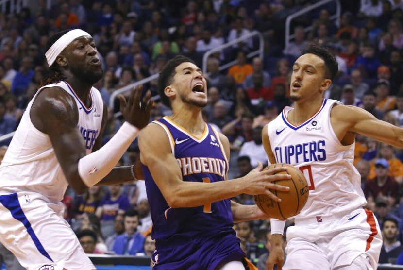 Guard Phoenix Suns Devin Booker (tengah) membawa bola diadang dua pemain Los Angeles Clippers.