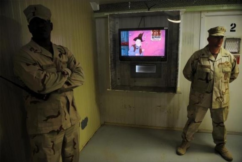 Guards stand next to a television showing a cartoon as journalists visit the movie room at the Camp Four detention facility at the U.S. Naval Station Guantanamo Bay December 10, 2008.