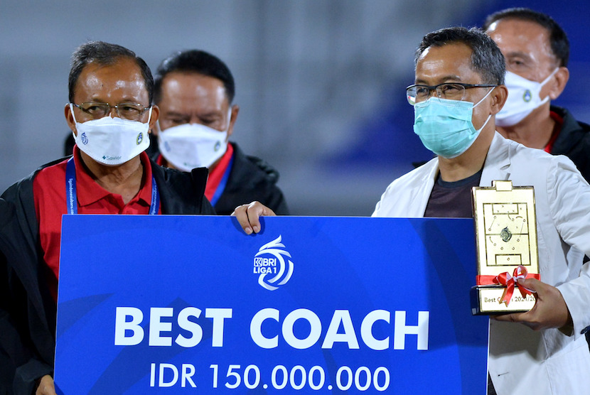 Gubernur Bali Wayan Koster (kiri) menyerahkan piala Pelatih Terbaik Liga 1 kepada Pelatih Persebaya Surabaya Aji Santoso (kanan) di Stadion Kapten I Wayan Dipta, Gianyar, Bali, Kamis (31/3/2022). Aji Santoso dinobatkan menjadi Pelatih Terbaik Liga 1 2021/2022. Aji, satu dari dua pelatih lokal yang tersisa di Liga 1.