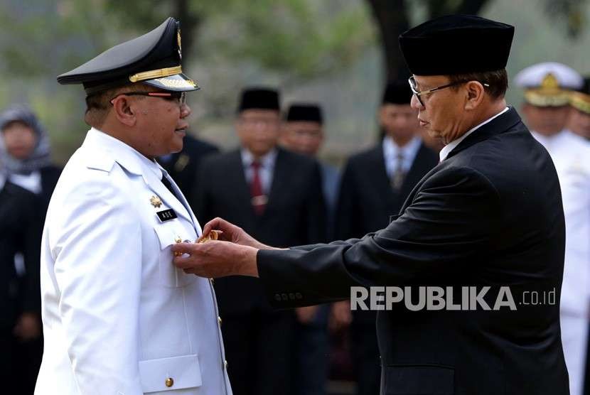 Gubernur Banten Wahidin Halim (kanan) menyematkan tanda jabatan saat melantik Penjabat (Pj) Wali Kota Serang Ade Aryanto (kiri) di Serang, Rabu (3/10).