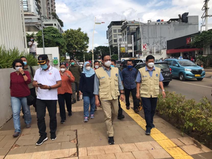 Gubernur DKI Anies Baswedan berbincang dengan petugas yang sedang menangani genangan di kawasan Kemang, Jakarta Selatan, Ahad (21/2).