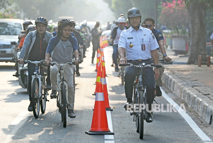 Gubernur DKI Jakarta Anies Baswedan (kanan) berbincang dengan warga ketika bersepeda di Jakarta.