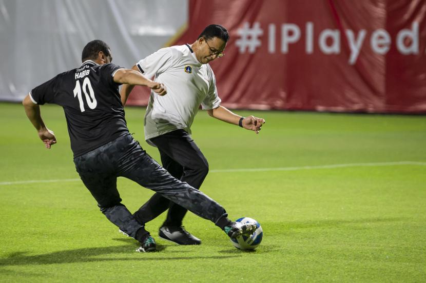 Gubernur DKI Jakarta Anies Baswedan (kanan) berusaha melewati hadangan pesepak bola tim DPRD DKI Jakarta saat uji coba lapangan latih di Jakarta International Stadium, (JIS) di Tanjung Priok, Jakarta Utara, Kamis (28/10/2021). Pertandingan persahabatan yang digelar PT Jakarta Propertindo (Jakpro) Perseroda tersebut adalah bagian langkah pembuktian bahwa dua lapangan latih JIS yang berstandar internasional kini sudah bisa dimanfaatkan untuk berbagai kegiatan masyarakat. 