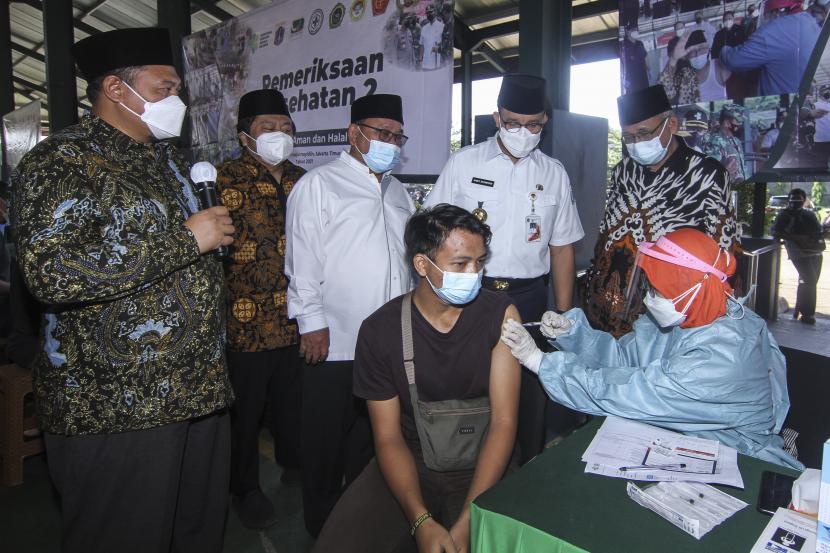 Gubernur DKI Jakarta Anies Baswedan (kedua kanan berdiri) bersama Ketua Umum DPP LDII Chriswanto Santoso (kanan) melihat proses penyuntikan vaksin COVID-19 di Sentra Vaksin Ponpes Minhaajurrosyidiin, Jakarta, Kamis (9/9/2021). Kunjungan tersebut dalam rangka meninjau kegiatan vaksinasi COVID-19 dosis kedua dengan target 1500 orang per hari untuk santri dan masyarakat sekitar guna mencapai mencapai kekebalan kelompok (Herd Immunity) di Indonesia.