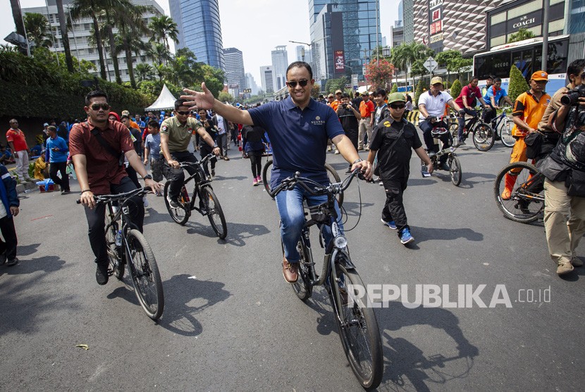 Gubernur DKI Jakarta Anies Baswedan melambaikan tangan saat meninjau Hari Bebas Kendaraan Bermotor (HBKB) di kawasan Bundaran HI, Jakarta, Ahad (3/11/2019). 