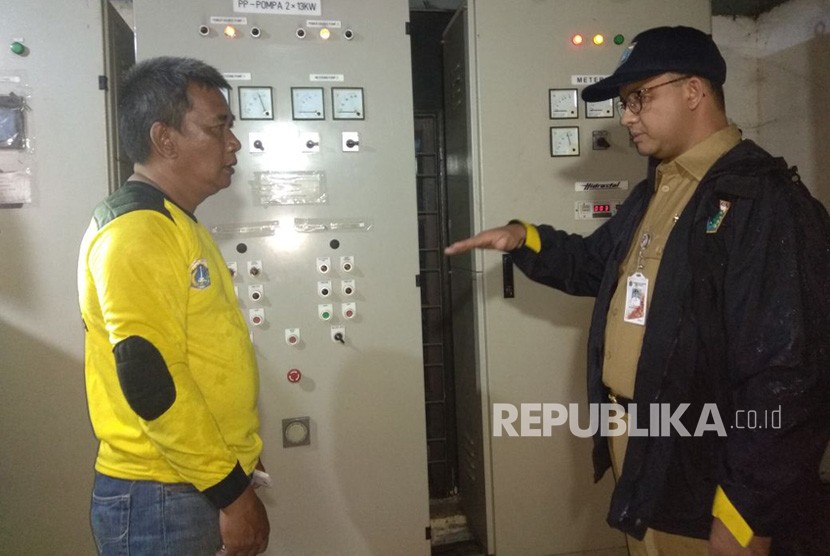 Gubernur DKI Jakarta Anies Baswedan saat meninjau panel listrik mesin pompa yang rusak ditemani Operator Pompa Mulyadi. 