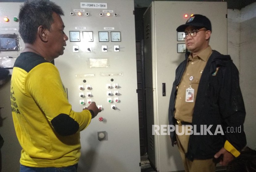 Gubernur DKI Jakarta Anies Baswedan saat meninjau panel listrik mesin pompa yang rusak ditemani Operator Pompa Mulyadi. 