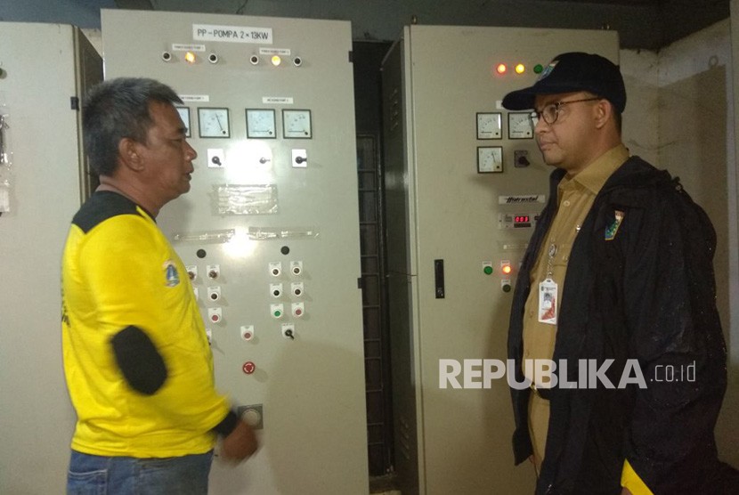 Gubernur DKI Jakarta Anies Baswedan saat meninjau panel listrik mesin pompa yang rusak ditemani Operator Pompa Mulyadi. 