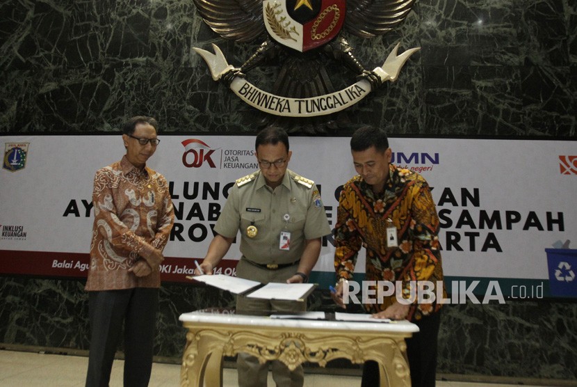 Gubernur DKI Jakarta Anies Baswedan (tengah) bersama Direktur Bisnis Konsumer BNI Anggoro Eko Cahyo (kanan) menandatangani nota kesepahaman Terkait Tata Kelola Berbasis Masyarakat yang Dituangkan dalam Gerakan Ayo Menabung dengan Sampah yang disaksikan oleh Anggota Dewan Komisioner OJK Tirta Segara (kiri) di Balai Agung, Jakarta, Senin (14/10/2019).