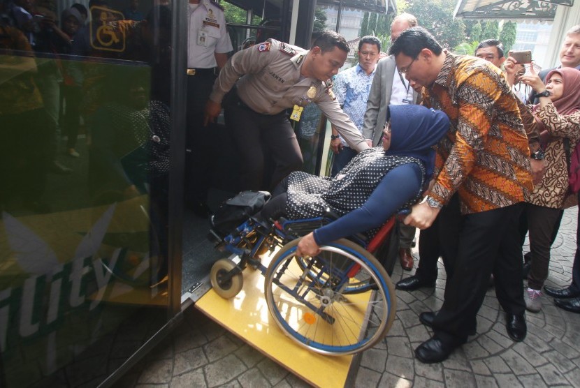 Gubernur DKI Jakarta Basuki Tjahaja Purnama (kanan) mendorong kursi roda penumpang disabilitas saat uji coba Scania Low Entry City Bus di Jakarta, Jumat (11/3).