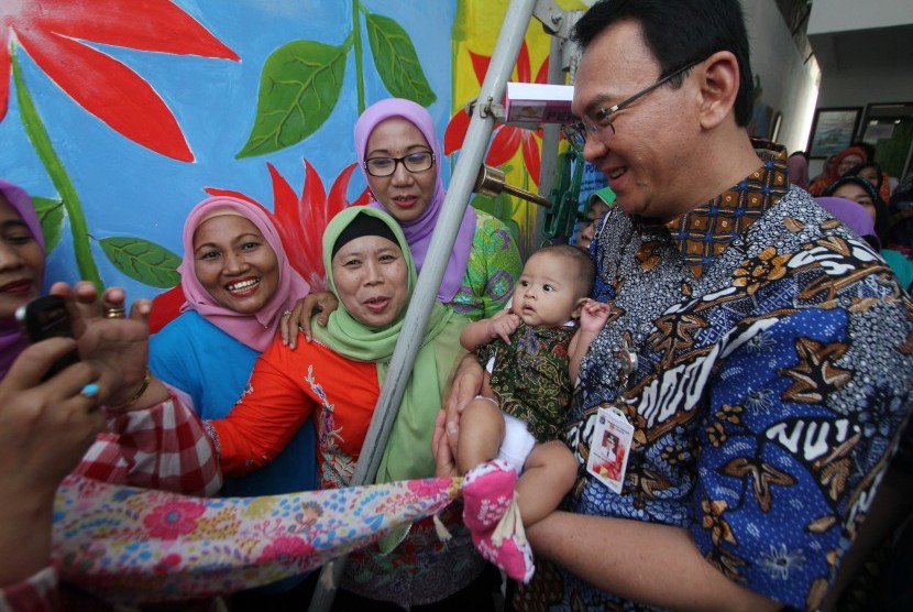 Gubernur DKI Jakarta Basuki Tjahaja Purnama (kanan) menggendong bayi usai meresmikan Ruang Publik Terpadu Ramah Anak (RPTRA) Bahari di Gandaria Selatan, Jakarta Selatan, Kamis (21/5).
